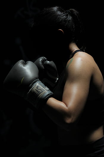 A powerful of a female boxer showcasing strength and determination in a dark setting. HD phone wallpaper