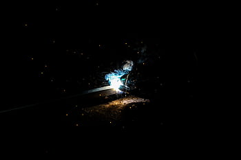 Vivid capture of welding sparks illuminating the night with striking contrast and atmosphere. HD wallpaper