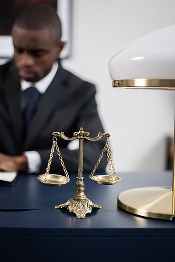 A professional lawyer working at his desk with scales of justice symbolizing fairness and law competence. HD phone wallpaper