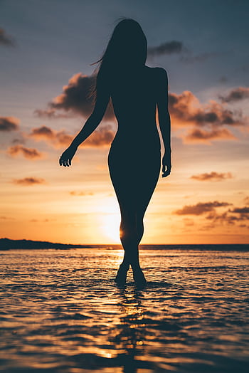 Graceful silhouette of a woman walking along Honolulu beach during a vibrant sunset. HD phone wallpaper