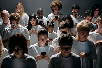 A diverse crowd of people using smarts, highlighting modern social connections and isolation. HD wallpaper