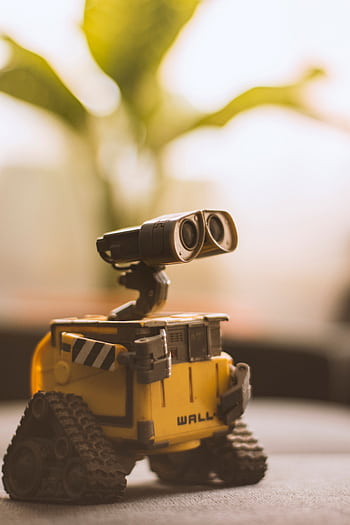 Charming toy robot placed on a desk, perfect for tech and nostalgia themes. HD phone wallpaper