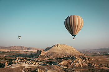 Hot air balloons float over the mesmerizing landscape of Cappadocia, Turkey at sunrise. HD wallpaper