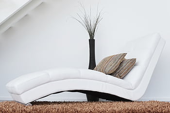 Elegant white lounge chair with cushions on plush carpet, perfect for relaxation. HD wallpaper