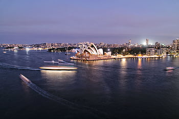A stunning view of the Sydney Opera House and harbor illuminated at twilight, showcasing city life and architecture. HD wallpaper