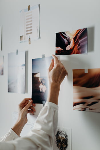 Hands arranging a mood board with various on an indoor wall. HD phone wallpaper
