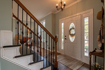 Inviting modern hallway with staircase, chandelier, and natural daylight. HD wallpaper