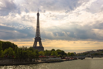 Stunning view of the Eiffel Tower at sunset with the River Seine and lush green trees. HD wallpaper