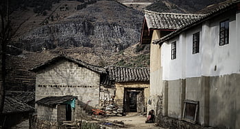 An old rustic house located in a rural village with mountainous backdrop, exemplifying traditional architecture. HD wallpaper