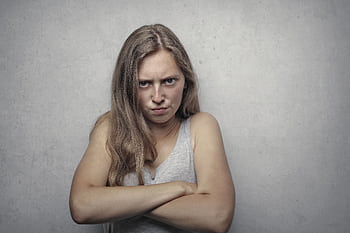 A woman with arms crossed showing a fierce expression against a gray background. HD wallpaper