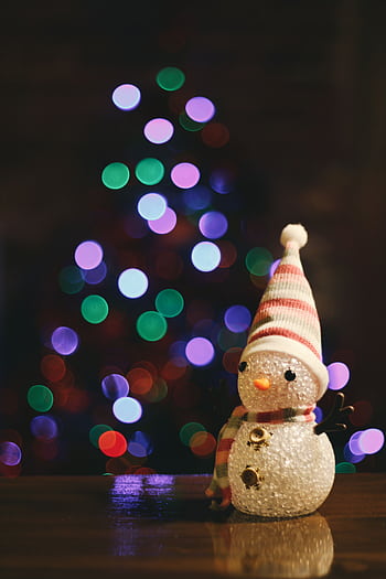 Charming snowman figurine with vibrant bokeh from Christmas lights in the background. HD phone wallpaper