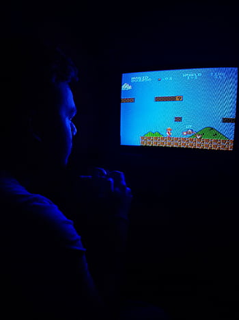 Man playing Super Mario Bros on TV, capturing retro gaming nostalgia. HD phone wallpaper