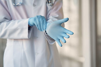 Close-up of a medical doctor wearing blue gloves for safety protection in a hospital setting. HD wallpaper