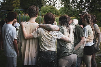 Group of teenagers bonding in a muddy team-building exercise outdoors. HD wallpaper