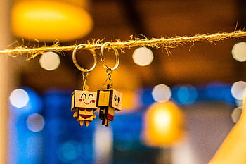 Close-up of cute toy keychains hanging on a string with bright bokeh lights in the background. HD wallpaper