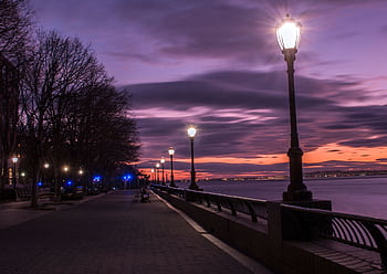 Dusk view of lamppost-lit path by the river at Robert Wagner Park, NYC. HD wallpaper