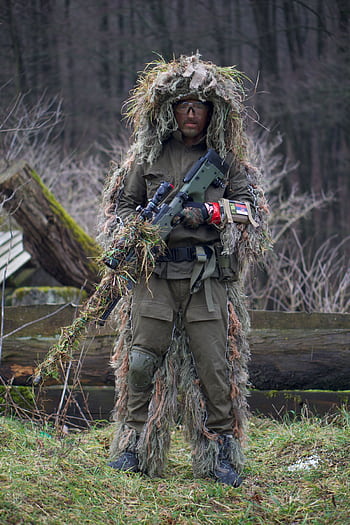 A soldier in camouflage and a ghillie suit holding a rifle in a forest setting. HD phone wallpaper