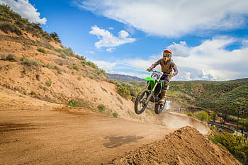Exciting motocross action with a biker jumping on a dirt track during a race. HD wallpaper