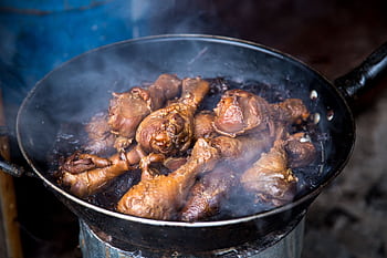 Close-up of juicy smoked chicken drumsticks cooking in a pan, creating mouthwatering steam. HD wallpaper