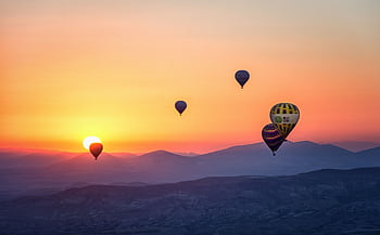 Stunning view of hot air balloons floating at sunrise over mountainous landscape. HD wallpaper