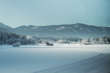 Peaceful winter scene with a snow-covered cabin and mountain backdrop, ideal for calming visuals. HD wallpaper