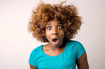Portrait of a surprised woman with curly hair in a teal top on a white background. HD wallpaper