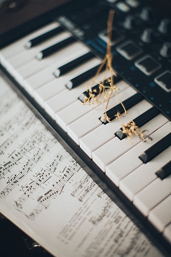 Close-up of piano keys with a flower and sheet music creates an artistic and musical ambiance. HD phone wallpaper