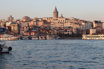 A breathtaking view of the Galata Tower and Istanbul's vibrant waterfront at sunset. HD wallpaper
