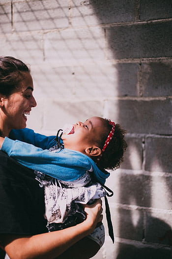 A mother and her child joyfully embrace, sharing a moment of happiness outdoors. HD phone wallpaper
