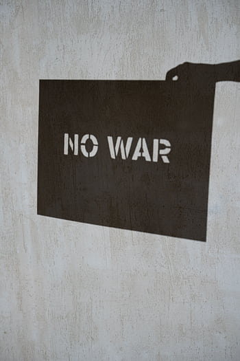 Shadow art depicting 'No War' message on a textured concrete wall, emphasizing peace. HD phone wallpaper