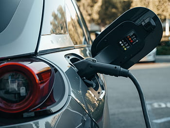 Close-up of an electric vehicle being charged, highlighting modern clean energy technology. HD wallpaper
