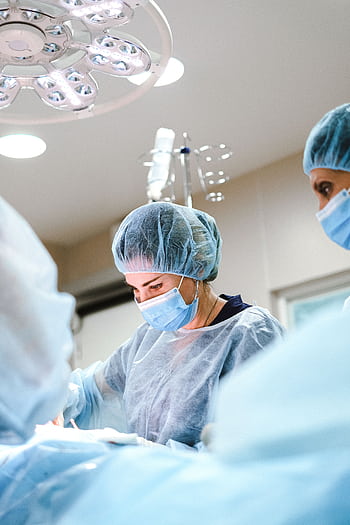A team of surgeons and nurses in protective gear performing an operation in a hospital. HD phone wallpaper