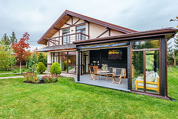 A beautiful suburban house featuring a lush green lawn and cozy patio area, ideal for relaxation. HD wallpaper