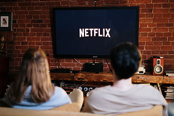 A couple relaxing and watching Netflix in a cozy living room setting. HD wallpaper