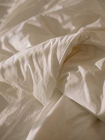 Close-up of crumpled white bed linen with soft natural lighting, evoking coziness. HD phone wallpaper