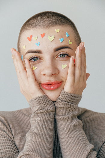 A bright portrait of a smiling person with heart stickers on their face. Ideal for Valentine's themes. HD phone wallpaper