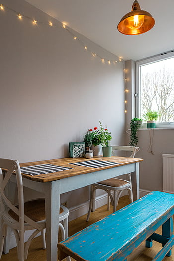 A bright and rustic dining room featuring wooden furniture, indoor plants, and warm lighting. HD phone wallpaper
