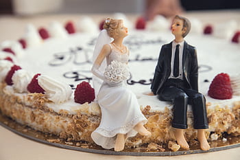 Close-up of a wedding cake with bride and groom figurines, raspberries, and whipped cream. HD wallpaper