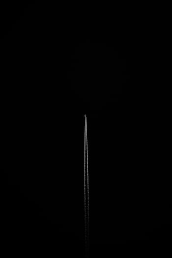 A striking capture of an airplane's contrail in a monochrome black setting, showcasing minimalism and contrast. HD phone wallpaper