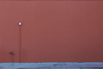 An orange-painted wall featuring a pipe and electrical outlet, perfect for minimalism themes. HD wallpaper
