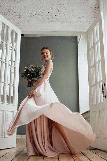 Joyful bride in an elegant gown twirling with bouquet in a bright indoor space. HD phone wallpaper