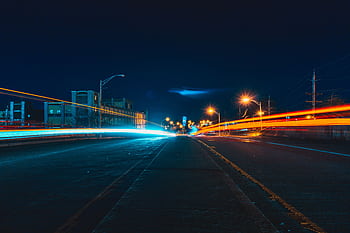 Captivating night cityscape with vibrant light trails on an urban highway, showcasing dynamic movement and city lights. HD wallpaper