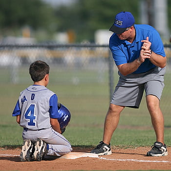 A young baseball player receives guidance from a coach during practice. HD phone wallpaper