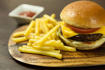 Delicious cheeseburger with fries and ketchup served on a wooden plate, perfect for lunch or snack. HD wallpaper