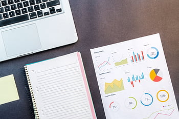 Top view of a laptop, notebook, and data charts on a table, ideal for business and work themes. HD wallpaper