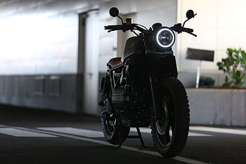 A sleek cafe racer motorcycle parked indoors with strong lighting contrast. HD wallpaper