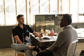 Two men having a focused business discussion in a sunlit office space. HD wallpaper