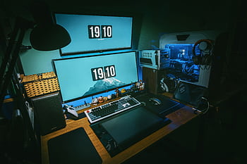 A sleek gaming desk setup featuring dual monitors, keyboard, and gaming PC in a dimly lit home office. HD wallpaper