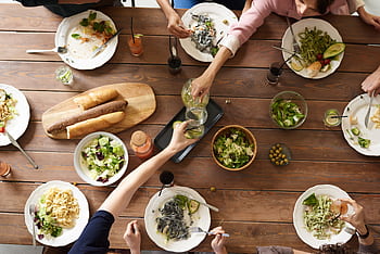 An overhead shot of a dining table featuring various pasta dishes and salads shared by a group. HD wallpaper