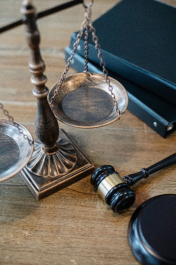 Detailed shot of a gavel, scales of justice, and legal books on a wooden table, symbolizing law and order. HD phone wallpaper